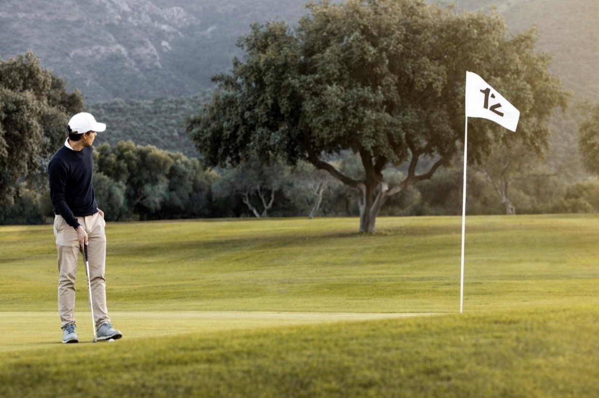 Golfer standing on green near flagstick