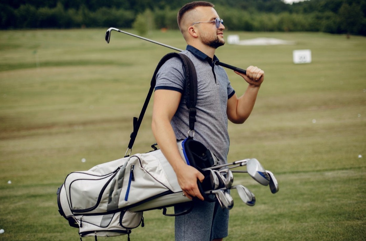 Golfer carrying golf bag on the range